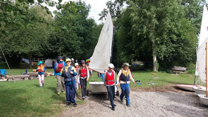 Kinder eines Segelcamps Bodensee tragen ein Boot