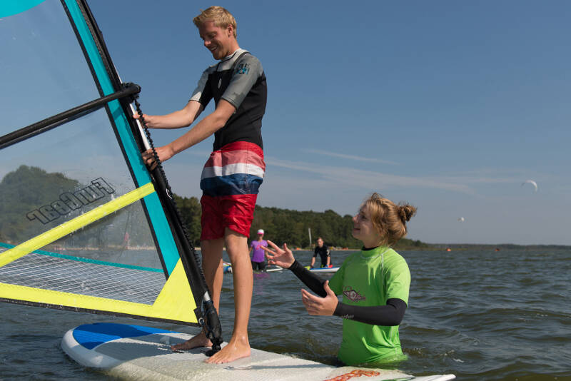 Einem Teilnehmer im Surfcamp wird erklärt, wie er das Segel halten muss