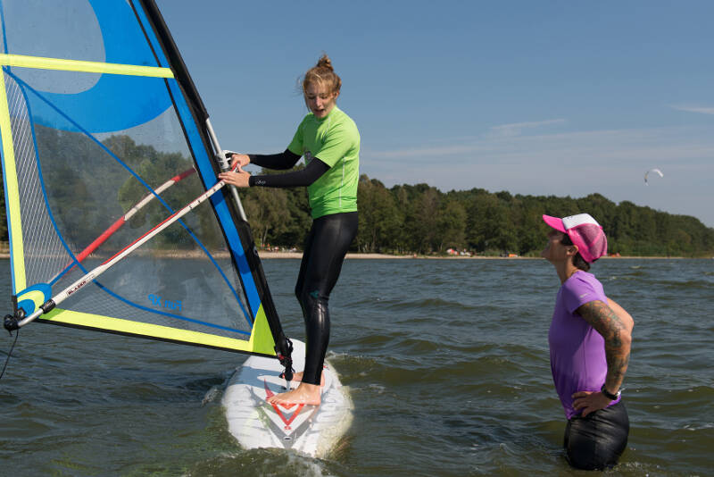Einer Teilnehmerin wird die Haltung auf dem Windsurfbrett im Sportcamp erklärt