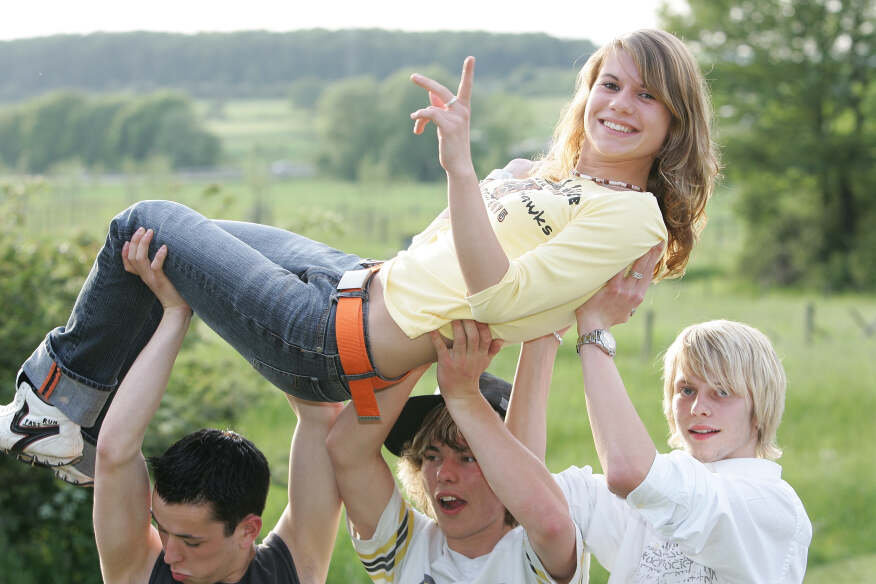 Drei Jungen tragen ein Mädchen