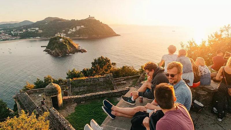 Jugendliche sitzen im Teenscamp auf einer Mauer an der Küste von Frankreich