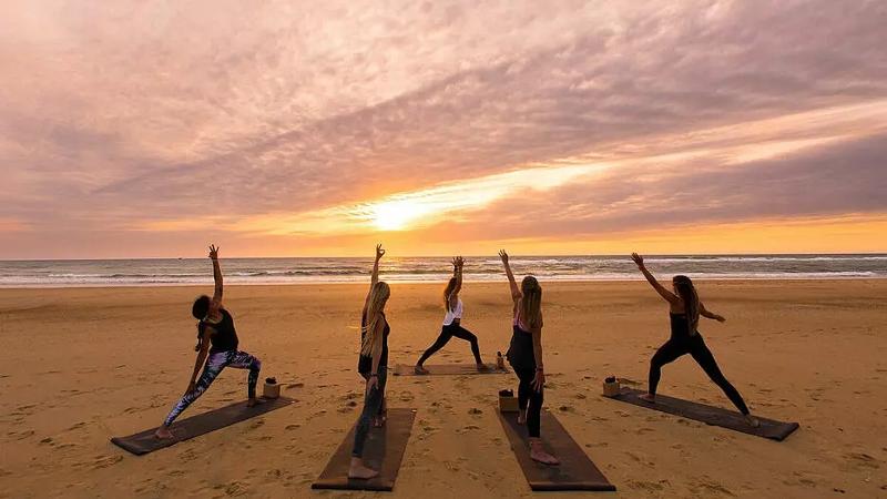 Ein paar Mädchen machen im Surf-Camp Südfrankreich am Strand Yoga