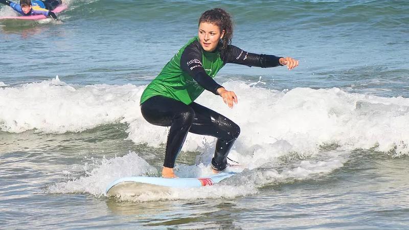 Ein Mädchen hält das Gleichgewicht im Surf-Camp Südfrankreich auf dem Board im Wasser