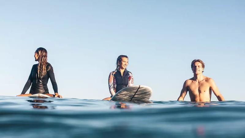 Jugendliche auf Sprachreise Frankreich ziehen mit ihren Surfboards auf das Meer zum Surfen