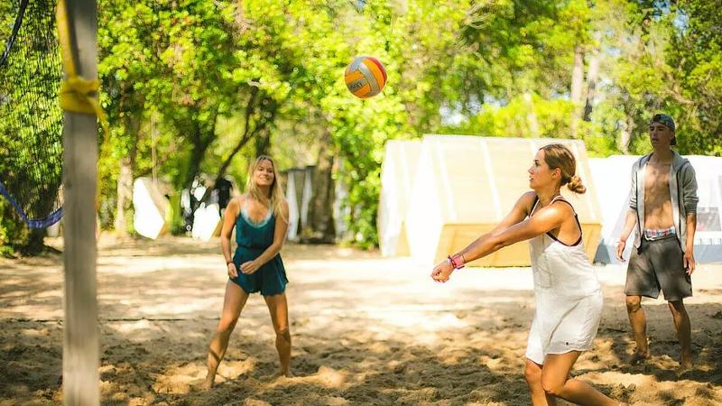 Mehrere Jugendliche spielen im Surf-Camp Frankreich eine Runde Volleyball im Camp
