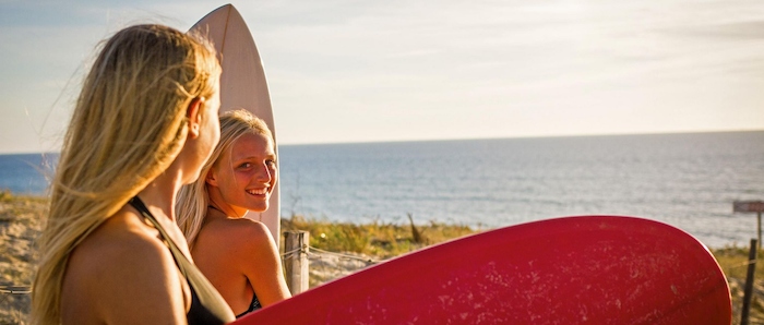 Mädchen mit Surfbrettern am Strand beim Surfcamp