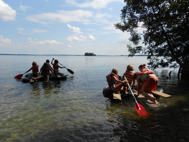 Kinder auf dem Schweriner See auf selbstgebauten Kanus vom Englisch Sprachcamp in Wiligrad