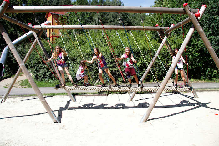 Mehrere Kinder spielen im Ferienprogramm Erlangen auf einer Balkenschaukel