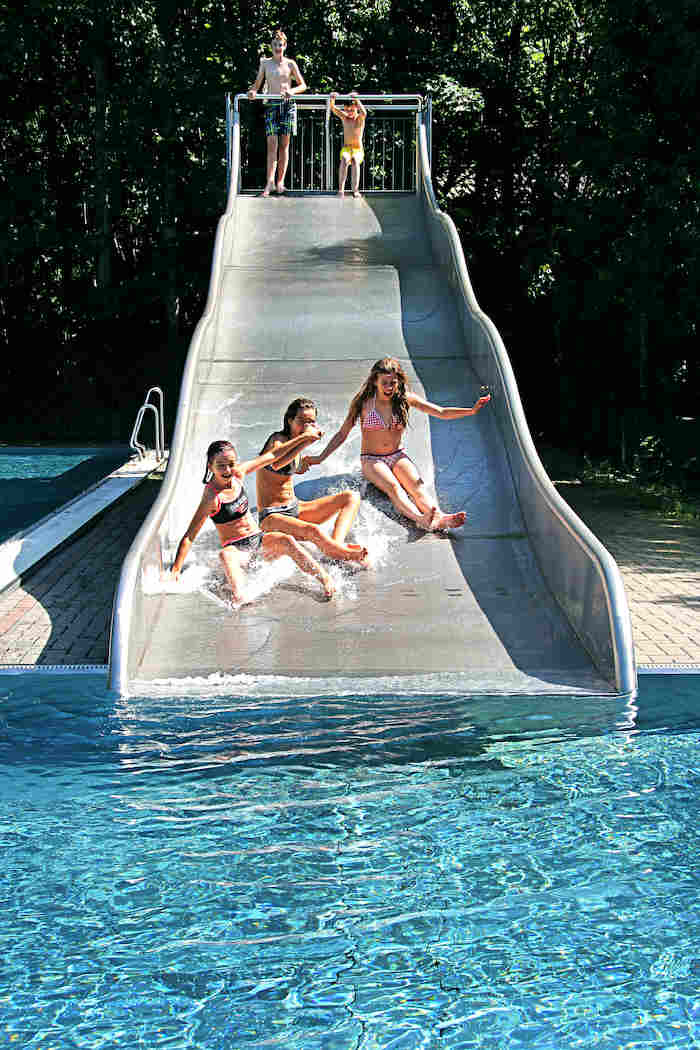 Drei Mädchen rutschen auf Rutsche in den Pool im Ferienlager in Limbach-Oberfrohna