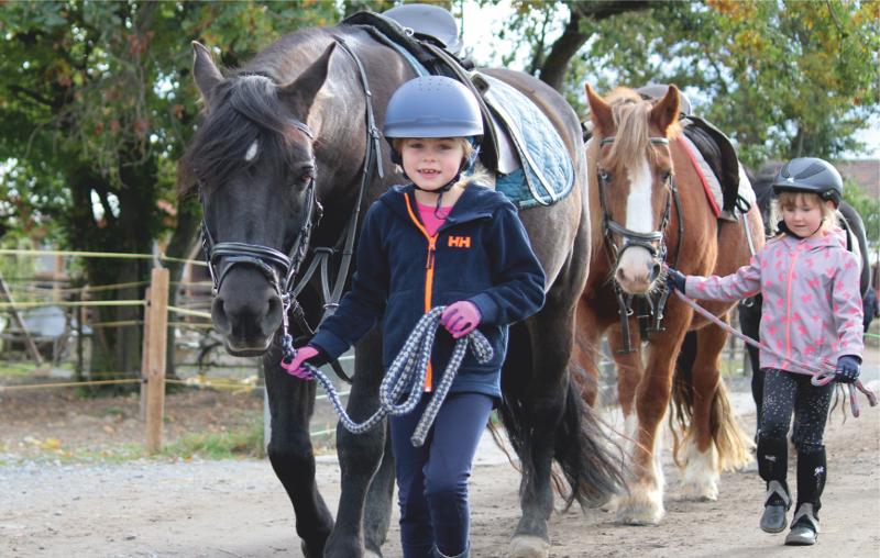Zwei Mädchen führen ihre Pferde im Ponycamp