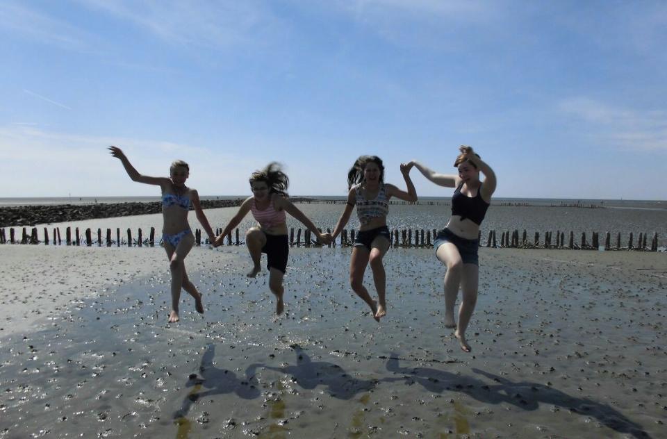 In den Reiterferien Schleswig-Holstein springen Mädchen am Strand