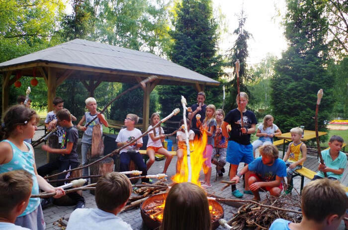 Teilnehmer eines Ferienlagers in den Osterferien Dresden grillen Stockbrot über einem Lagerfeuer 