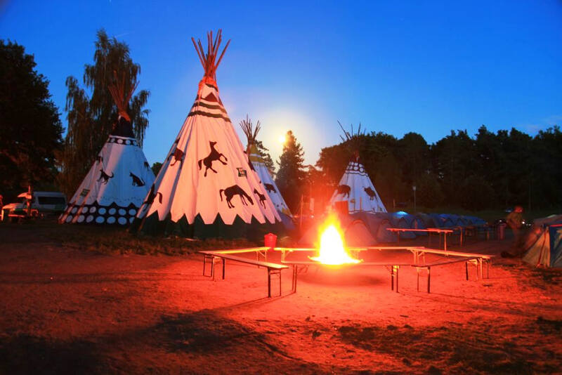 Ein Lagerfeuer prasselt vor den bemalten Tipis
