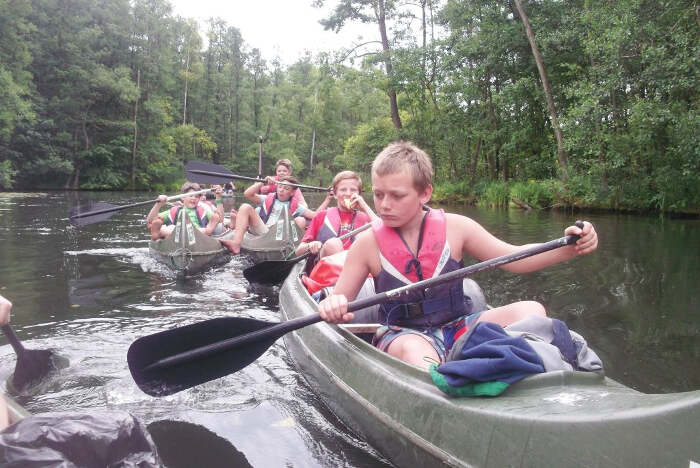Kinder paddeln in Kanus durch einen Kanal während des Ferienprogramms MV