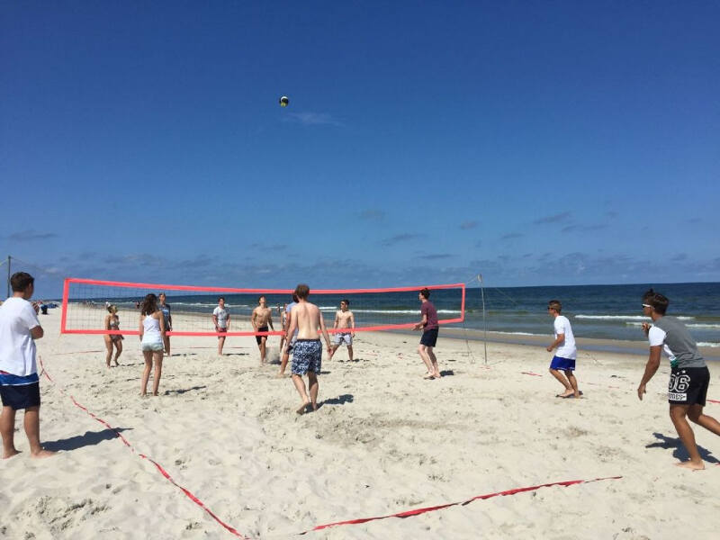 Die Teilnehmer der Jugendreise liefern sich am Strand der Ostsee ein Volleyballmatch während die Sonne scheint