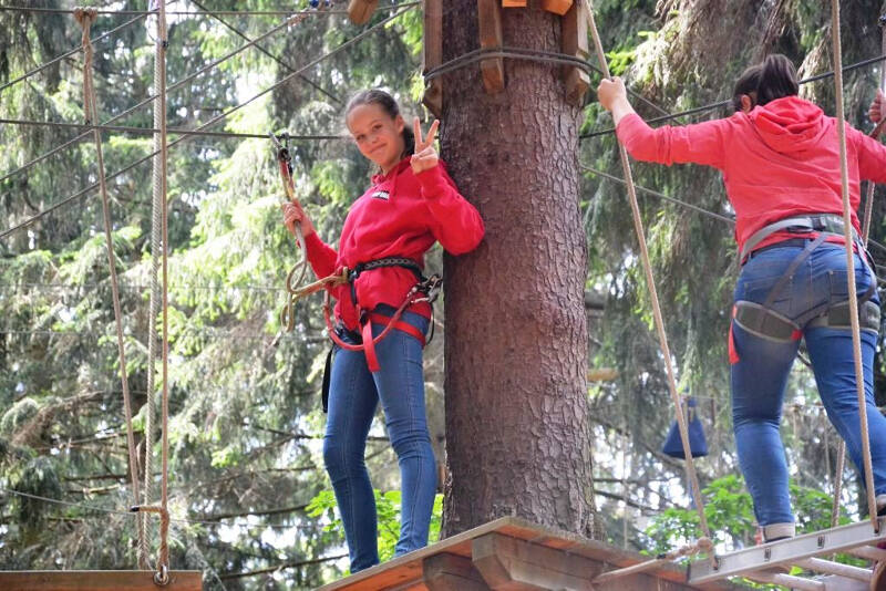 Ein Mädchen steht auf einer Plattform an einem Baum beim Klettern in Limbach-Oberfrohna