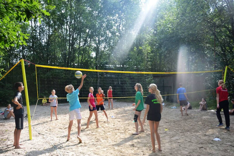 Mehrere Teilnehmer vom Ferienprogramm Ludwigshafen spielen in der Natur Volleyball