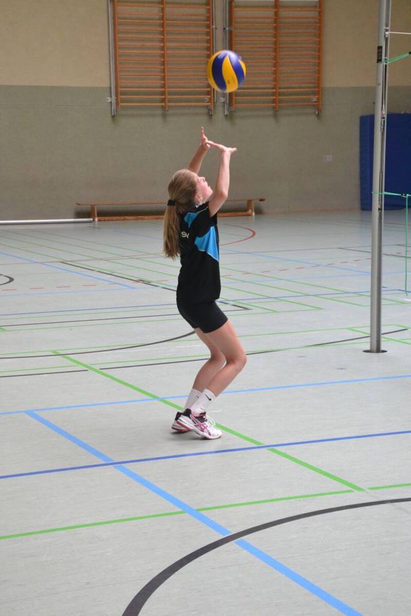 Ein Mädchen eines Volleyball Ferienlagers pritscht einen Ball.
