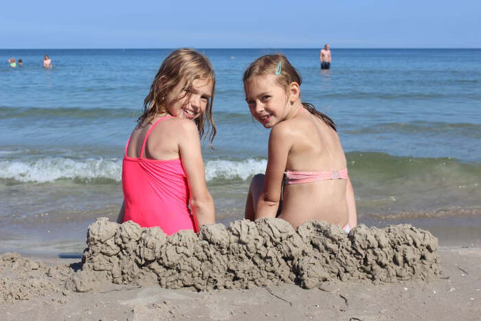 Zwei Mädchen sitzen am Strand auf Rügen.