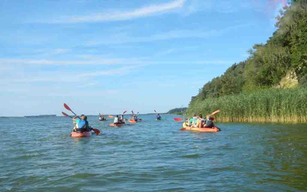 Eine Kanuflotte fährt im Feriencamp Berlin unter der Mittagssonne über den See