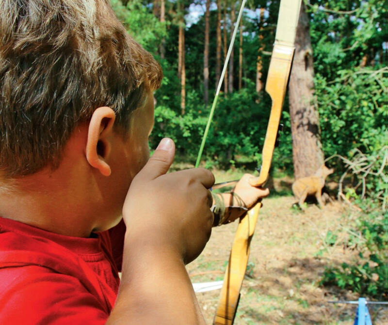 Junge zielt mit Pfeil und Bogen im Abenteuercamp am Beetzsee