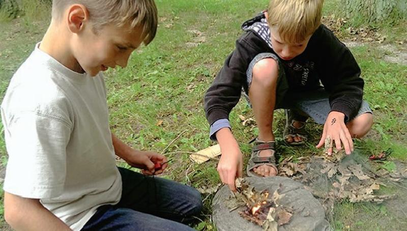 Jungs lernen wie man ein Lagerfeuer macht im Abenteuercamp