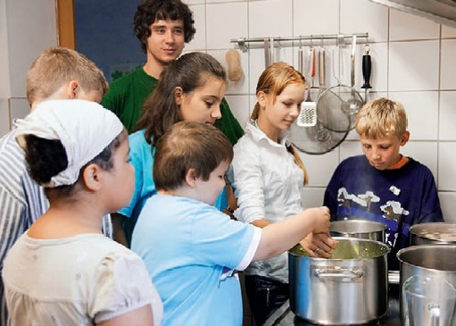 Kinder bereiten in der Küche Essen zu. 