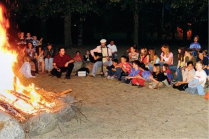 Kinder sitzen vor Lagerfeuer im Ferienlager in Mecklenburg-Vorpommern