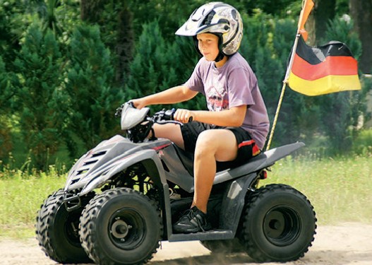 Ein Junge fährt auf einem Quad auf einem sandigen Weg