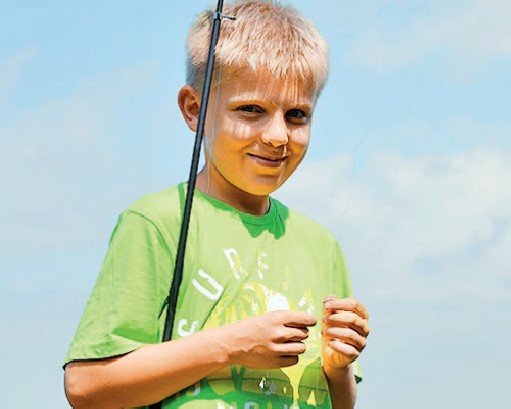 lächelnder Junge mit Angel in Natur im Loppin Angelcamp Ferienlager