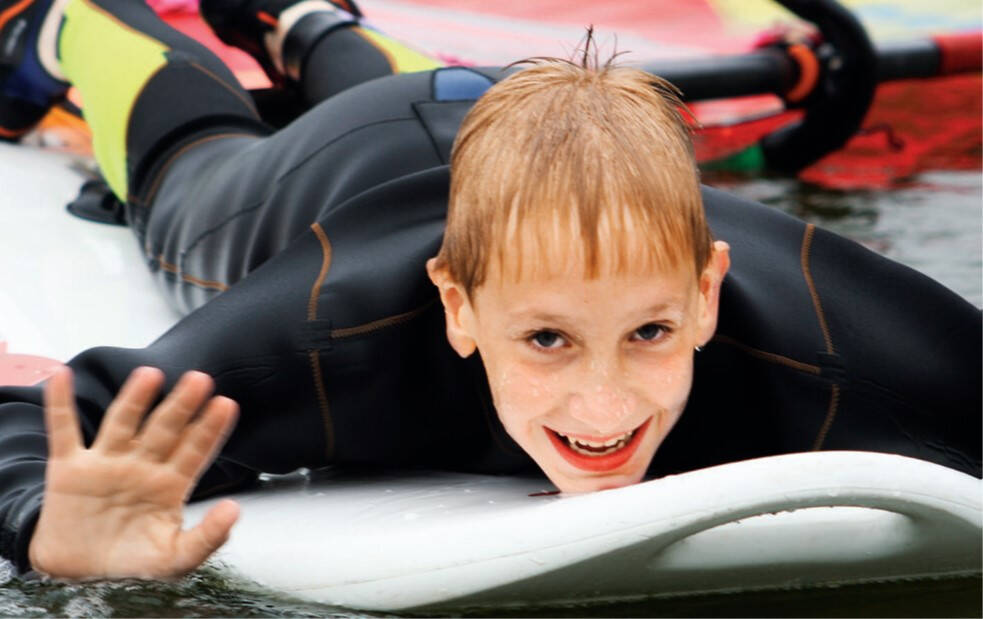 Junge liegt auf Board im Lütow Surfcamp