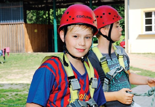 Kinder mit Kletterausrüstung lernen über Sicherheit beim Klettern im Sportcamp Gadow