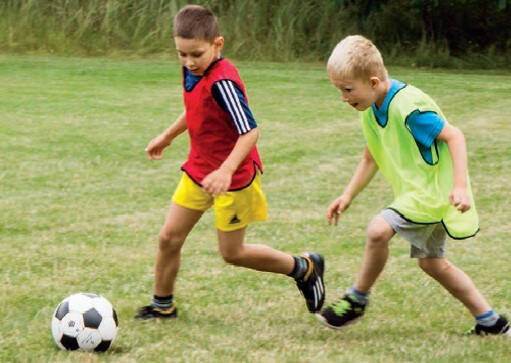 Kinder spielen Fußball auf Wiese im Störitzland Fußballcamp