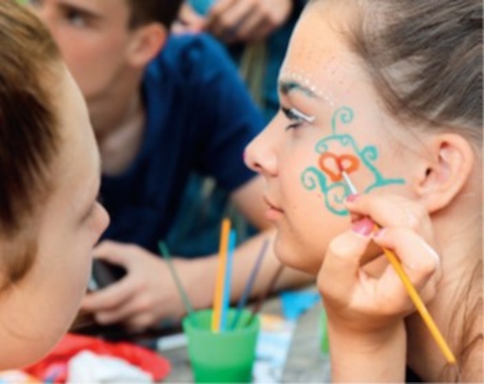Mädchen bemalen sich gegenseitig die Gesichter im Ferienlager an der Ostsee