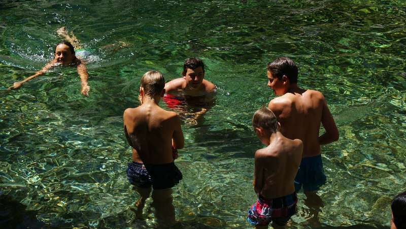 Kinder schwimmen und stehen am Ufer des Tauchcamps