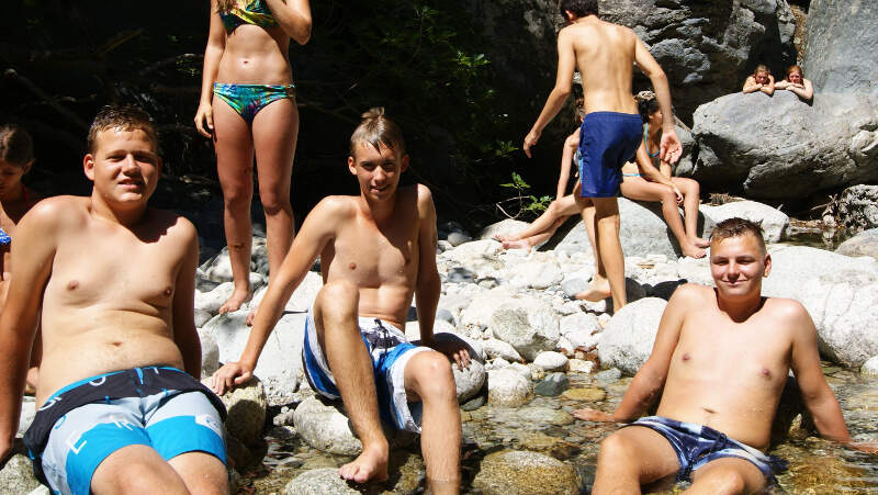 Jungs chillen beim Baden an Felsen auf Ferienfreizeit Korsika