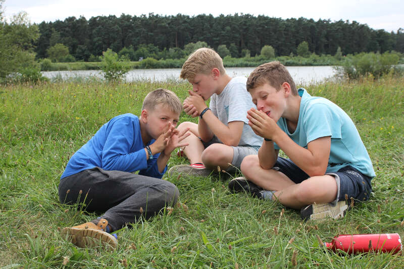 Jungs sitzen im Gras in der Kinderfreizeit Nürnberg