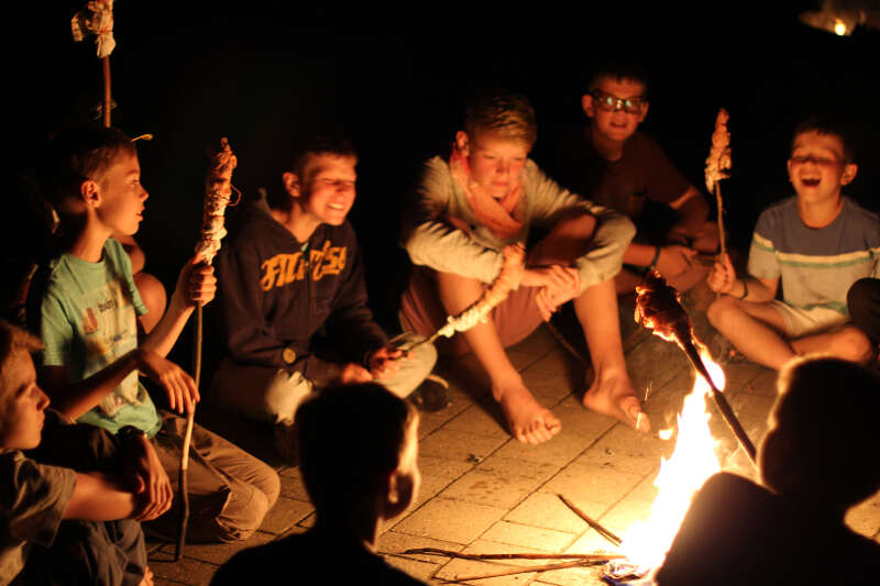Jungs sitzen mit Stockbrot am Feuer in der Kinderfreizeit Nürnberg