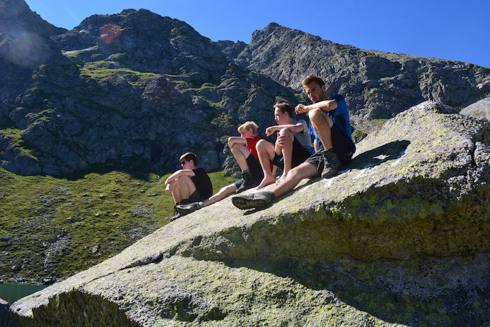 Feriencamp-Teilnehmer sitzen auf einem Felsen