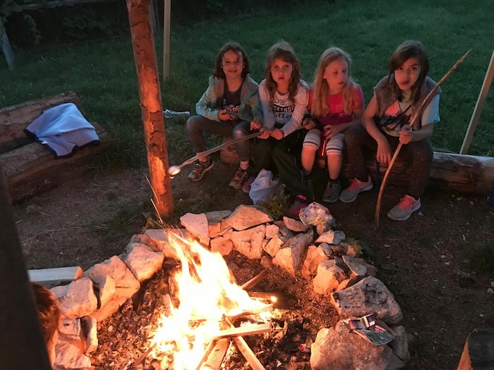 Kinder des Ferienprogramms München sitzen am Feuer
