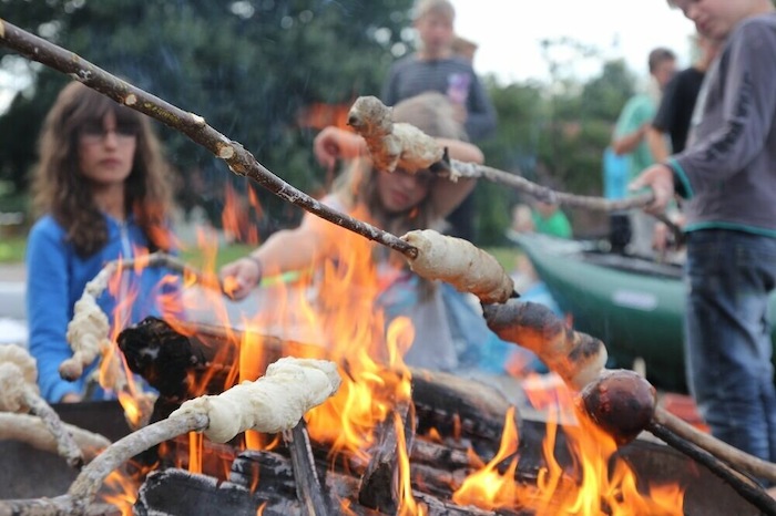 Die Gruppe der Feriencamps Partschefeld machen Stockbrot über dem Lagerfeuer. 