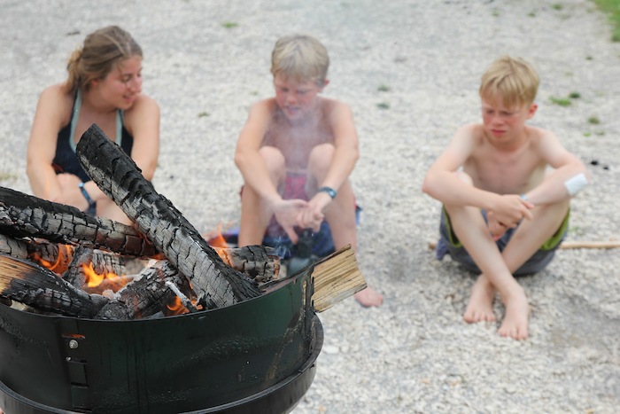 Drei Kids sitzen am Strand am Lagerfeuer in der Kinderfreizeit Nürnberg