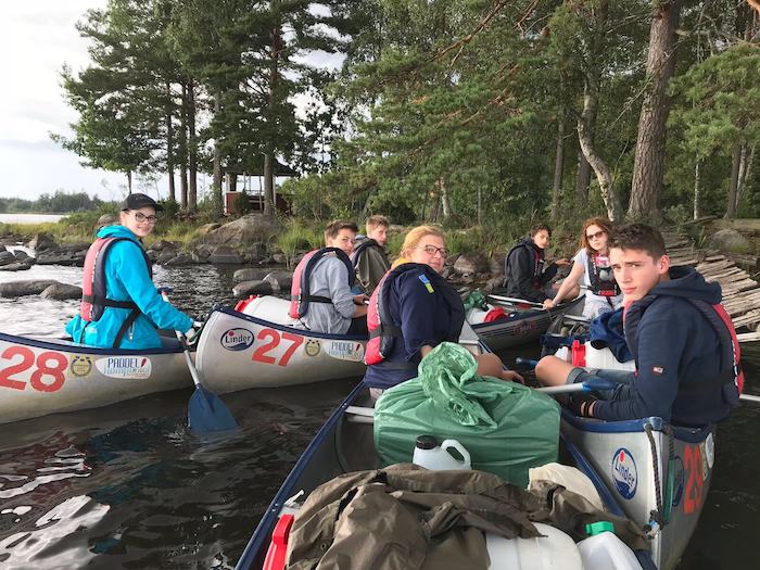 Kinder eines Abenteuer Forschercamps fahren Kanu
