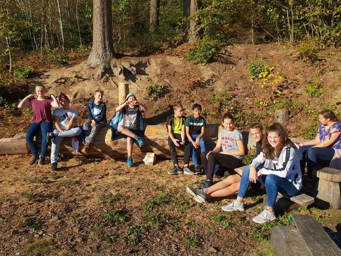 Kindergruppe sitzt am Waldrand auf der Ferienfreizeit in Belgien