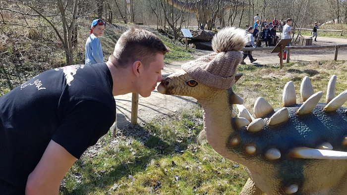 Junge gibt Dinosaurier-Statue einen Kuss auf der Ferienfreizeit in Rheinland-Pfalz
