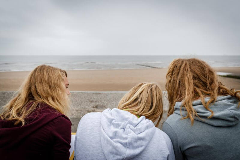 Drei Mädchen sitzen am Strand während ihrer Sprachreise Brighton