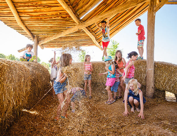 Kinder eines Feriencamps Stuttgart bewerfen sich mit Stroh
