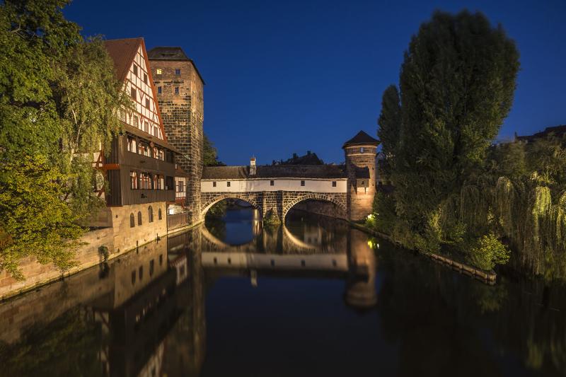 Eine alte Brücke wird nachts im Musicalcamp angeleuchtet