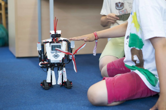 Witte robot op grond, jongetjes spelen ermee op creakamp.