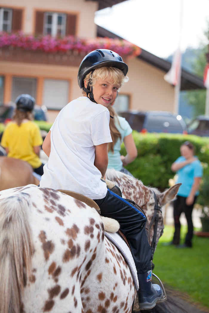 Junge reitet auf gepunktetem Pferd in den Reiterferien Österreich